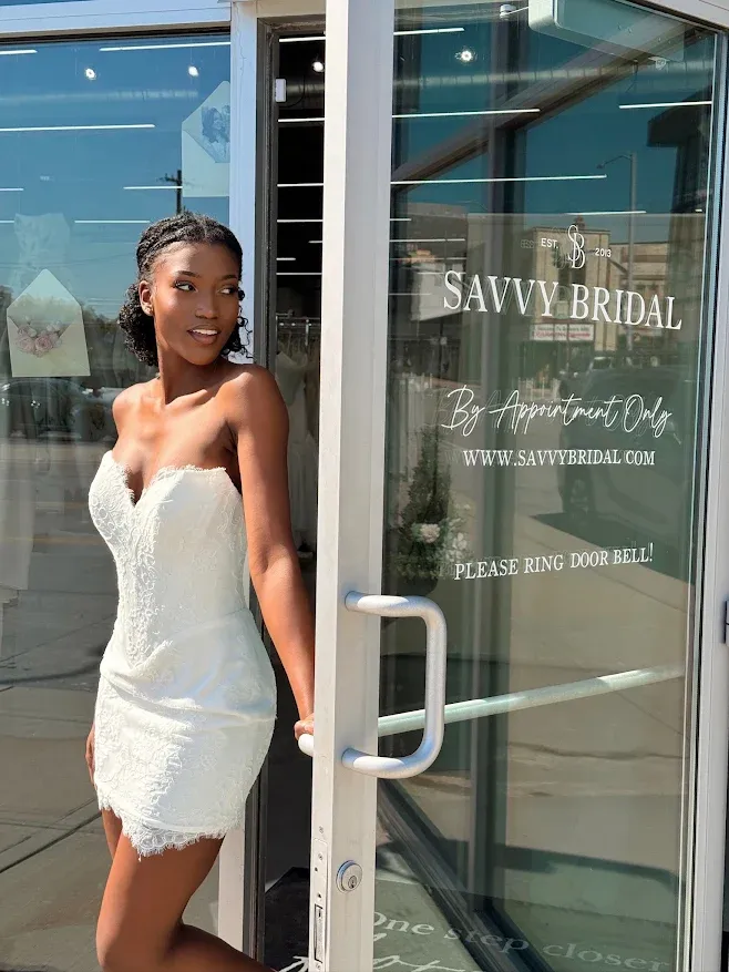 A bride in a lace mini dress at the Savvy Bridal front door