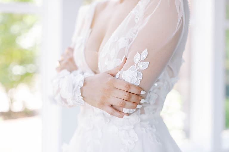 body of woman wearing wedding dress with arms crossed below her bust