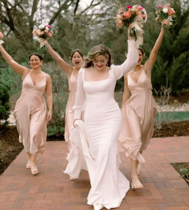 bride walking with bridesmaids and holding flowers