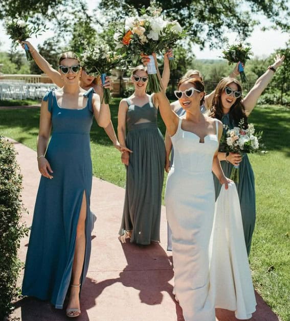 bride with bridesmaids in sunglasses and holding flowers