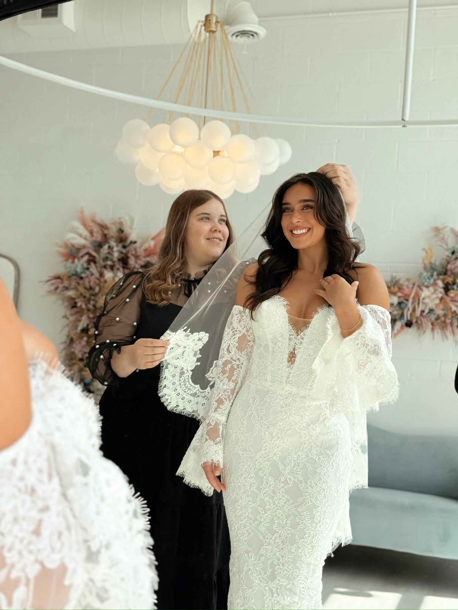 stylist assisting bride with her veil perfect paired with the beautiful gown during bridal appointment