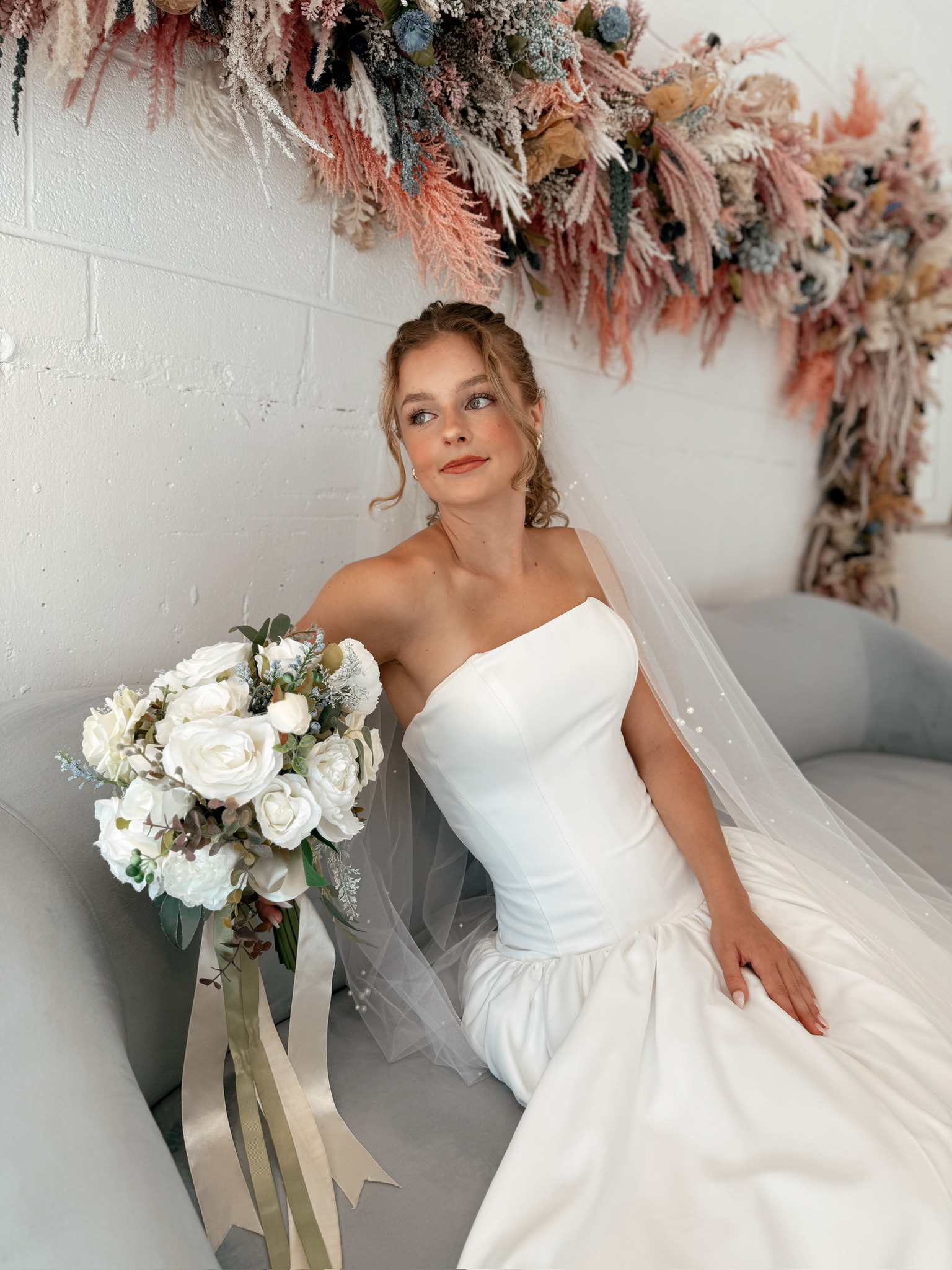 Chic strapless satin wedding gown paired with a delicate pearl veil