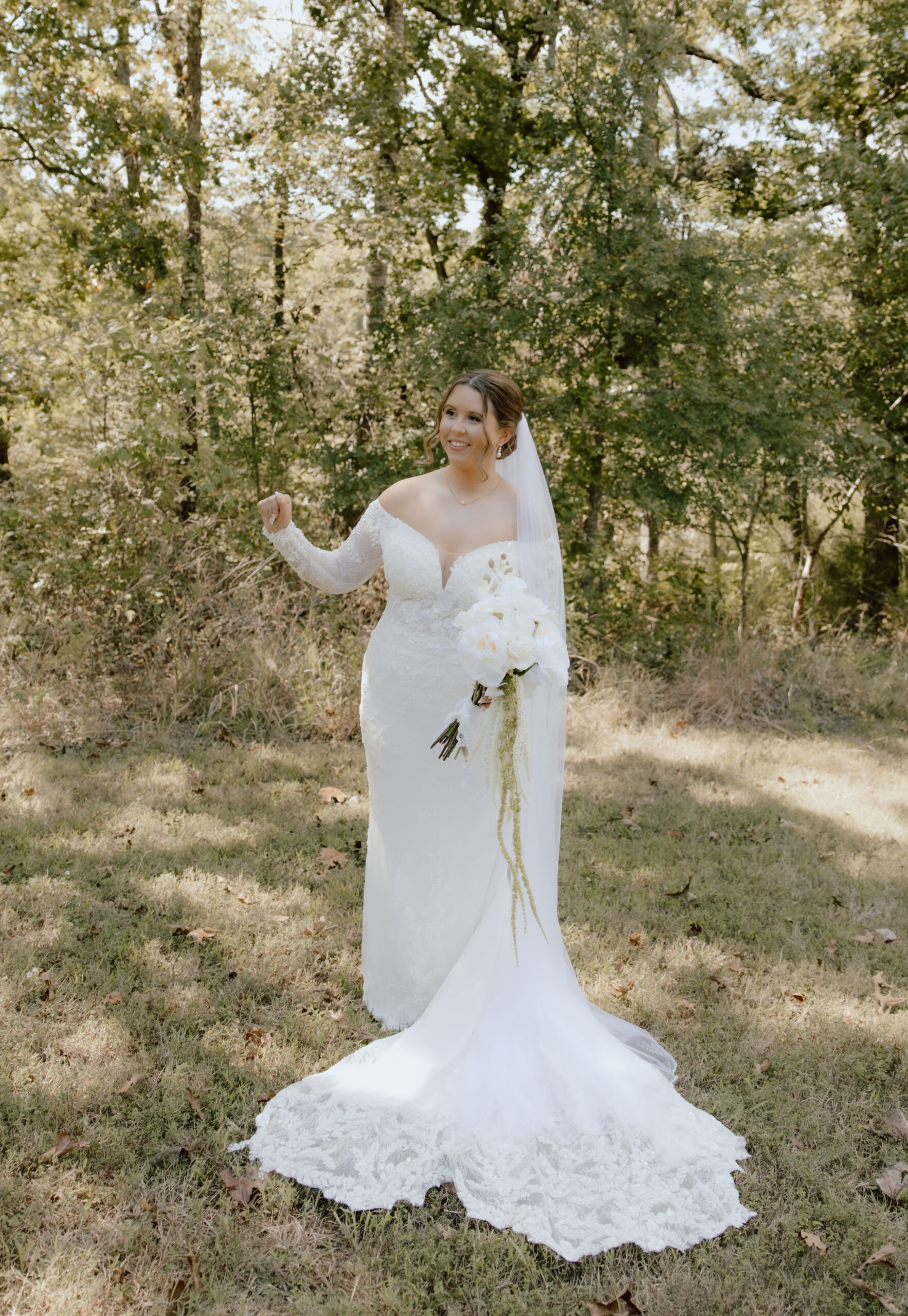 Stunning image of bride Lauren wearing her off-the-shoulder lace gown under the shade of beautiful trees.