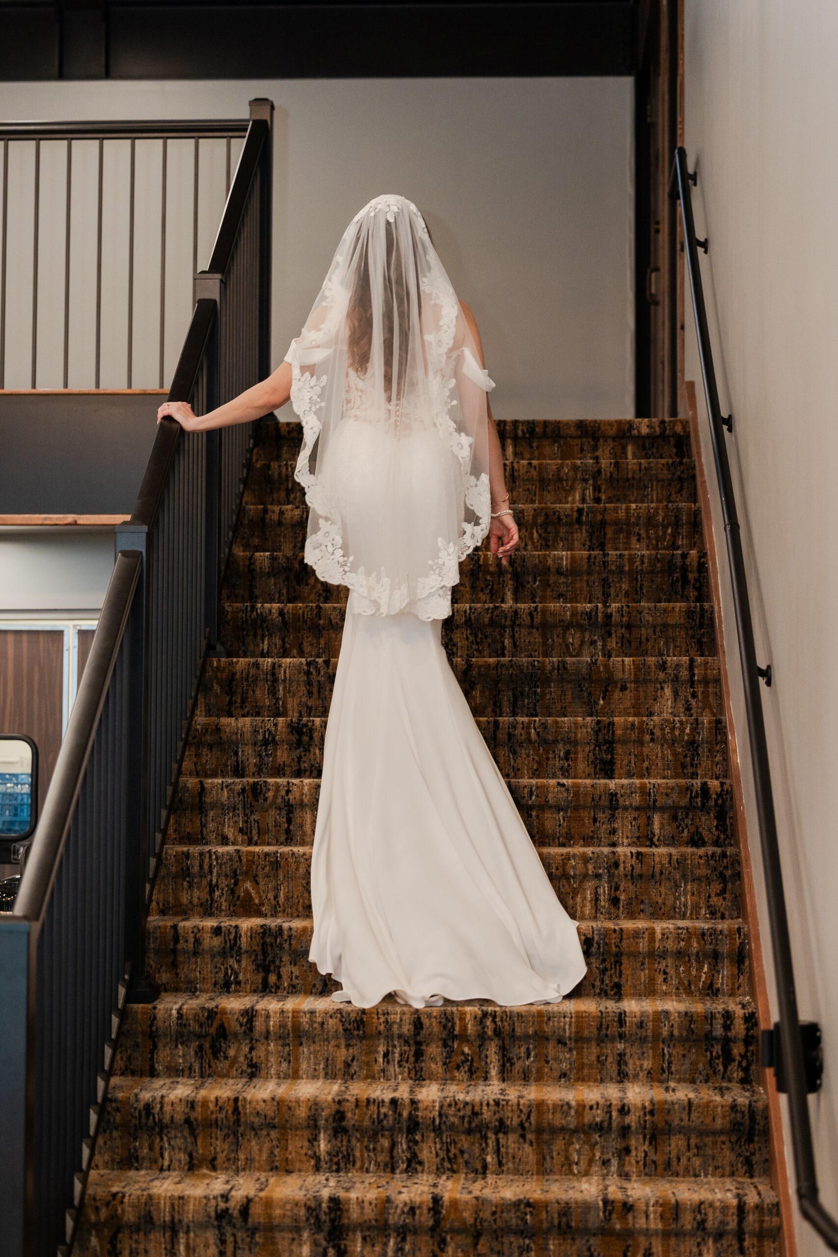 Savvy bride Mikayla walking upstairs showing the beauty of her bridal gown and lace tips veil.