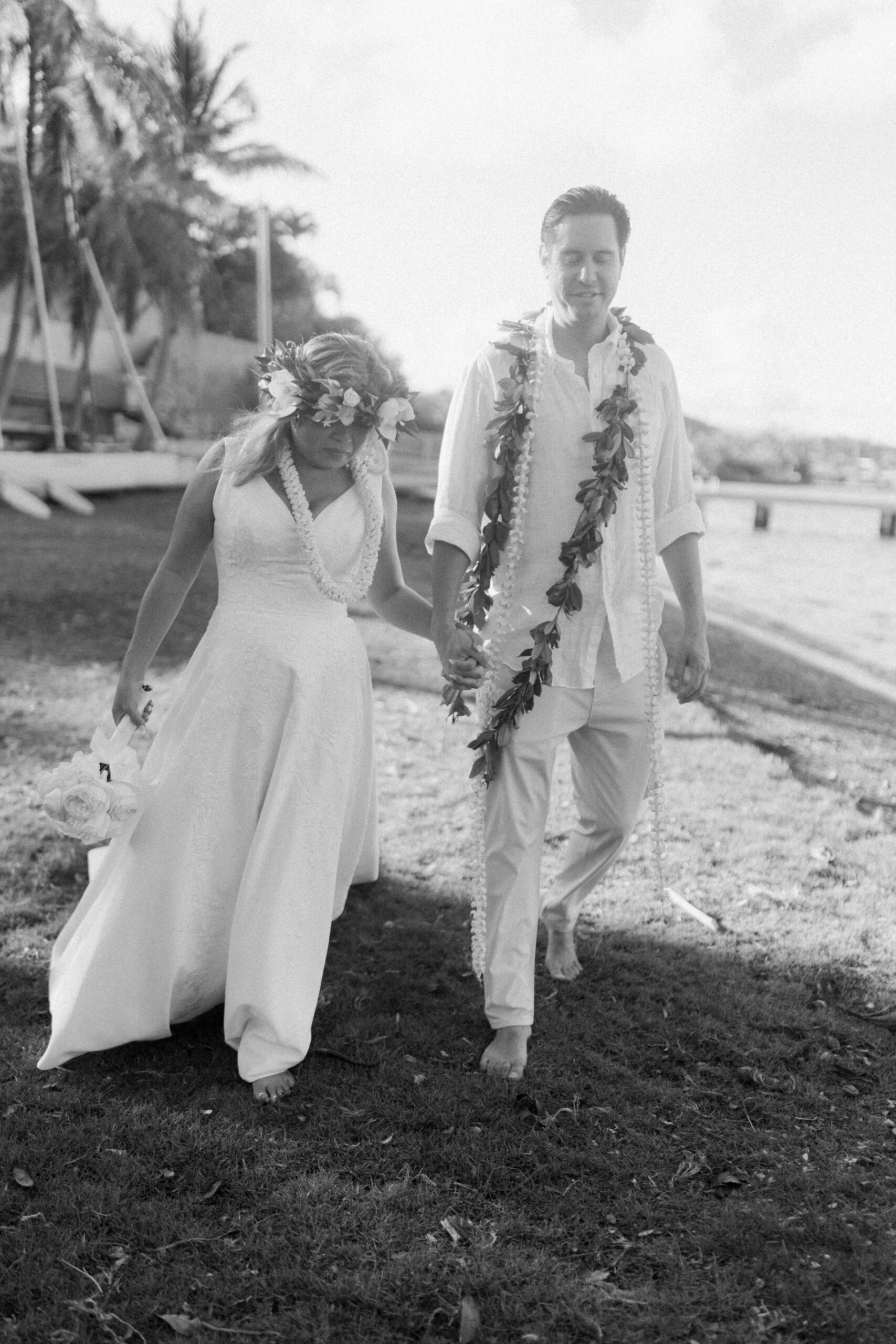 The couple was walking barefoot along the shore, hand in hand, leis around their necks, feeling the sand.