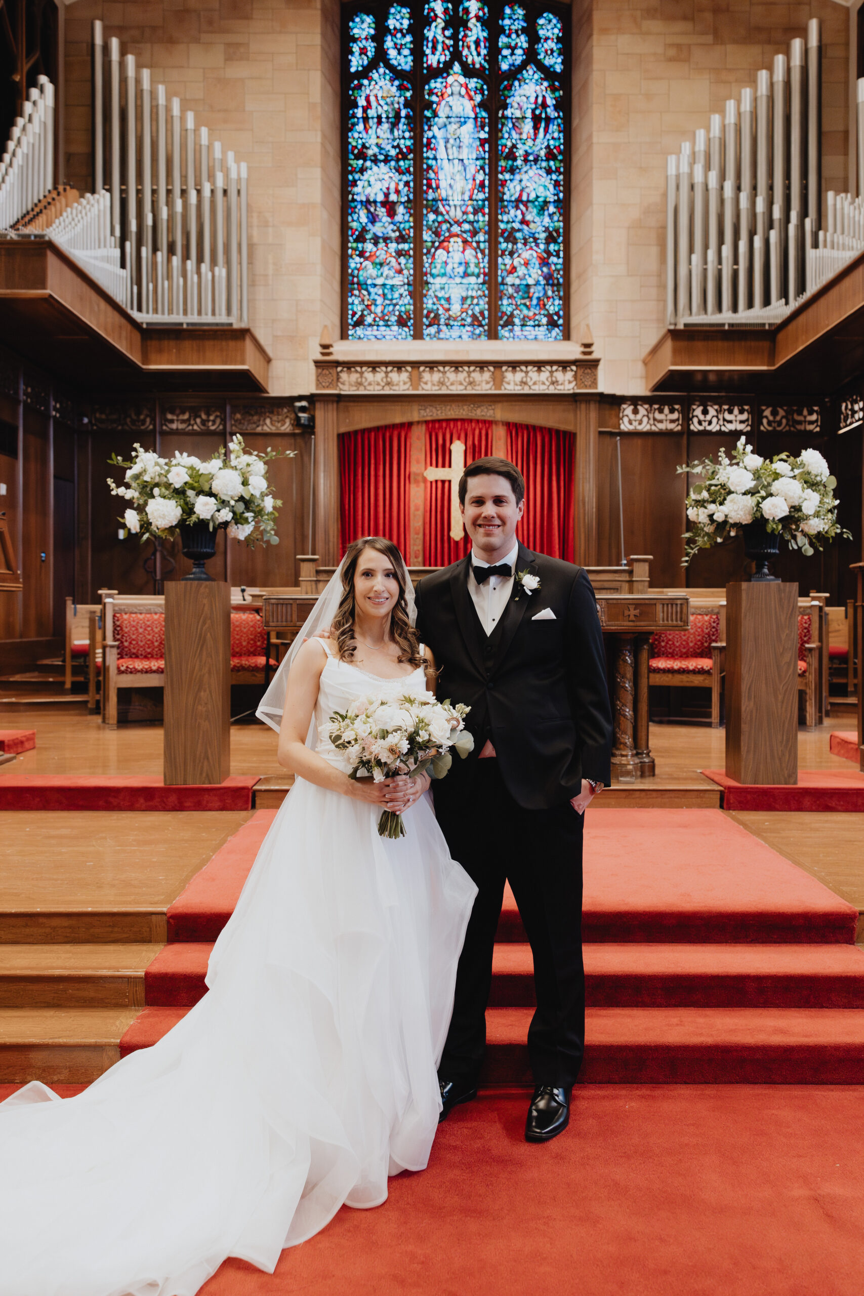 couple portrait photo inside the church. Surrounded by dark wood bookshelves and the soft glow of natural light from the large windows