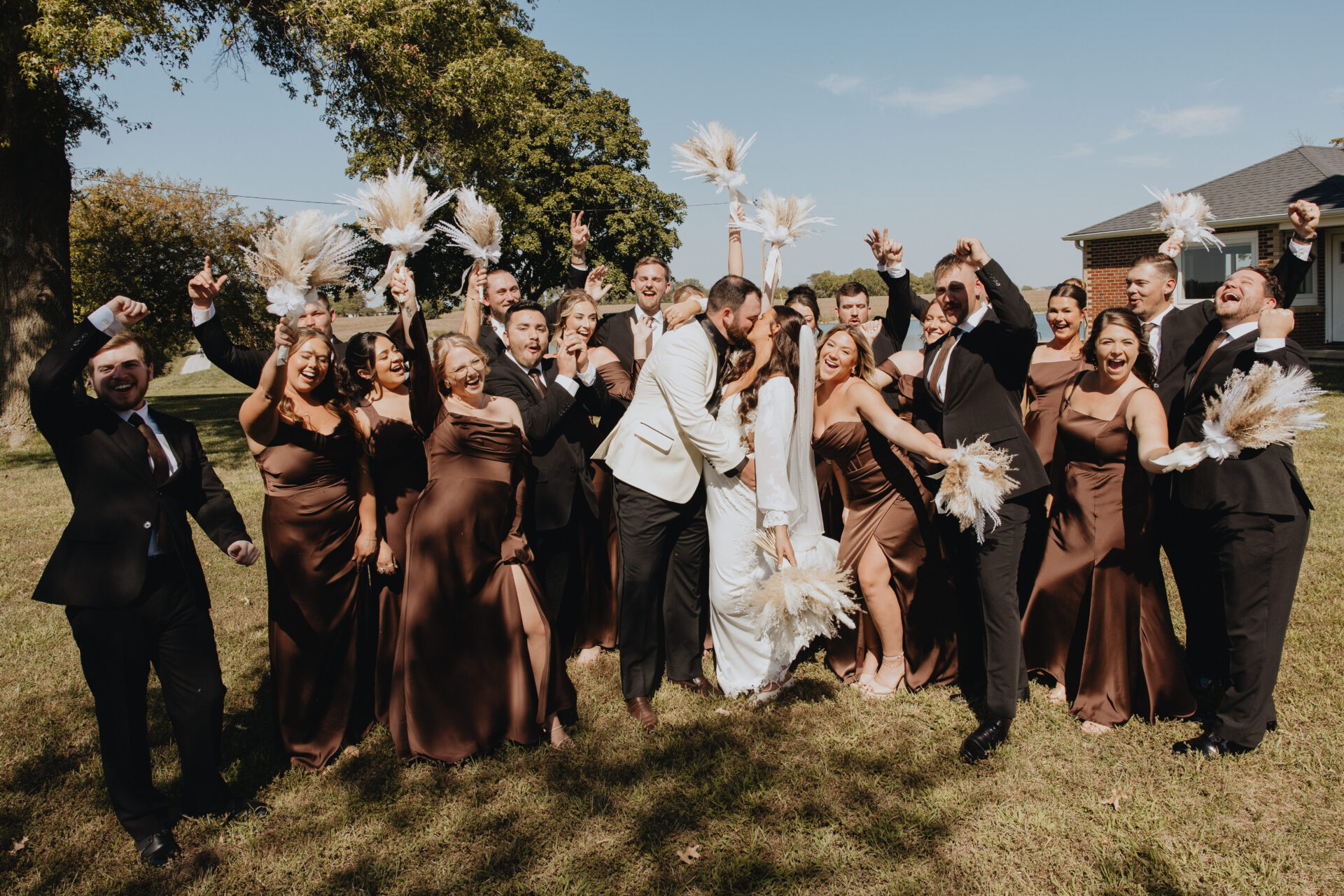 Kelsey and Colby’s boho-chic elegance theme wedding. The happy bridesmaids wear an earthy tones of the bridesmaids’ dresses contrasted beautifully with the dried pampas grass bouquets and groomsmen with all black tuxedos.