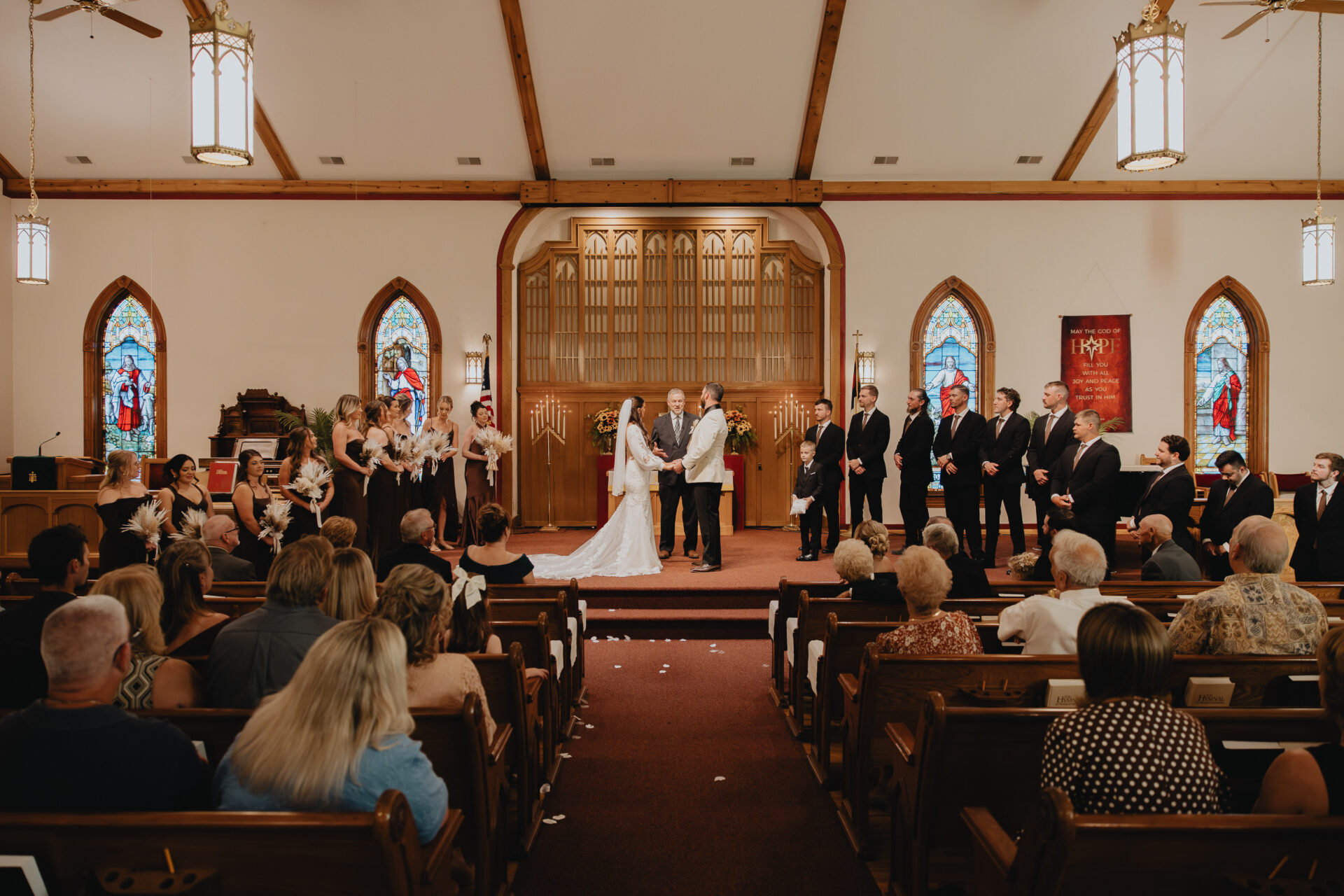 The wedding ceremony inside the warm wood-beamed ceilings and vibrant stained-glass windows of the church.