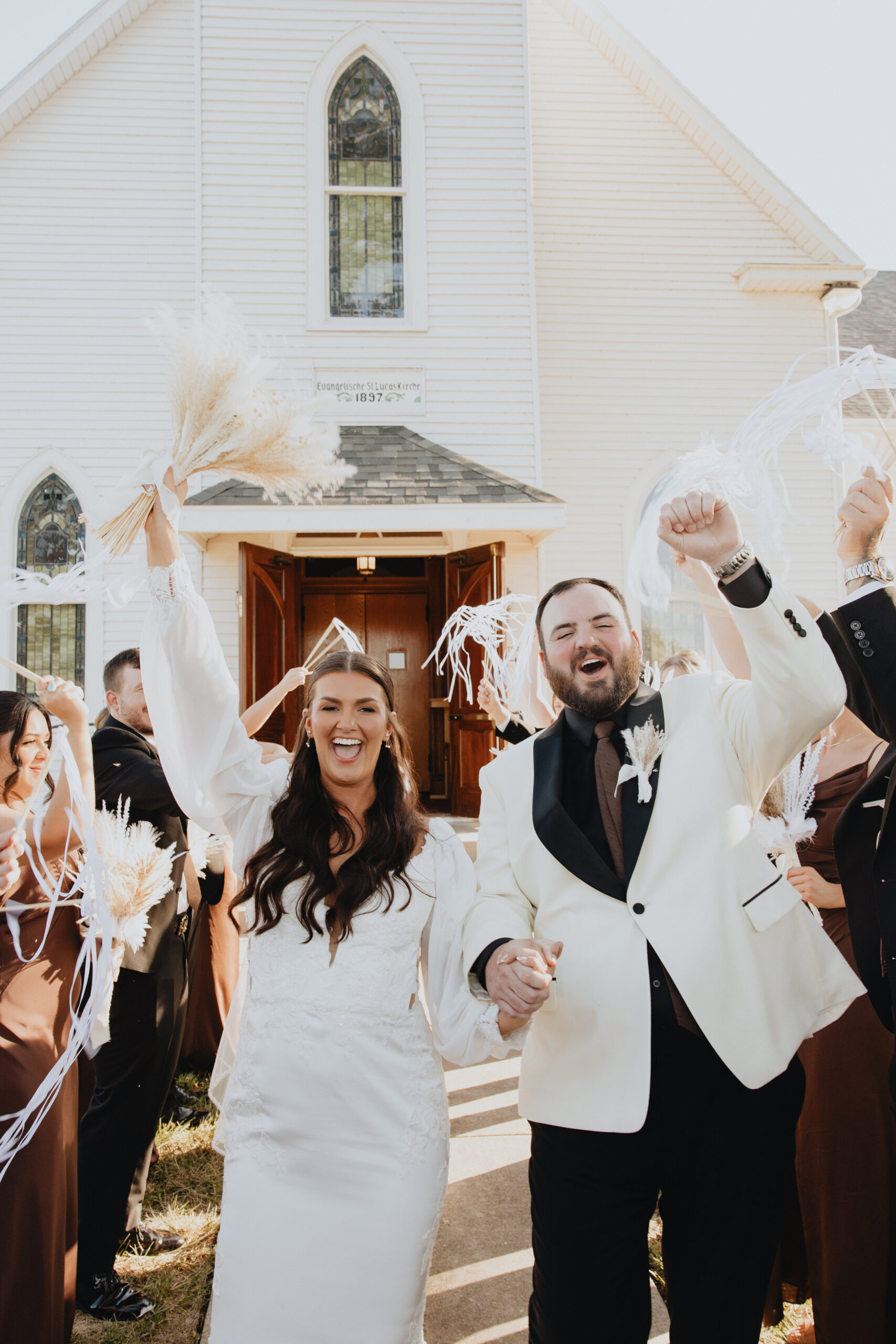 newlyweds Kelsey and Colby grand exit  happily walking outside the white church while the encourage cheering on them.