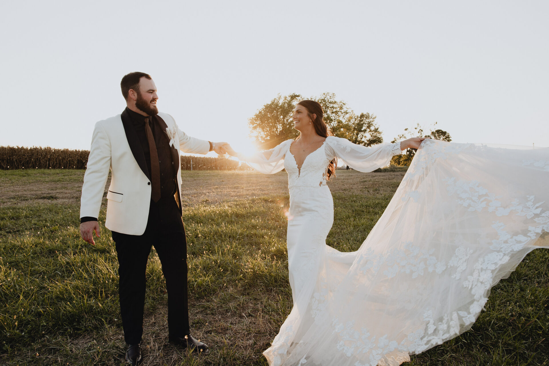 Colby stood out in a stylish white tuxedo jacket with black lapels holding hands with Kelsey while she twirl in her bridal gown, with the sun hitting the floral lace of her train
