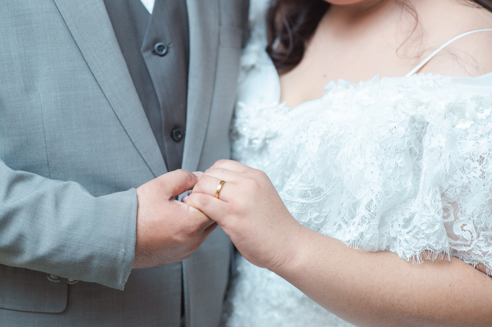 Plus-size bride in lace wedding dress olding hands with groom