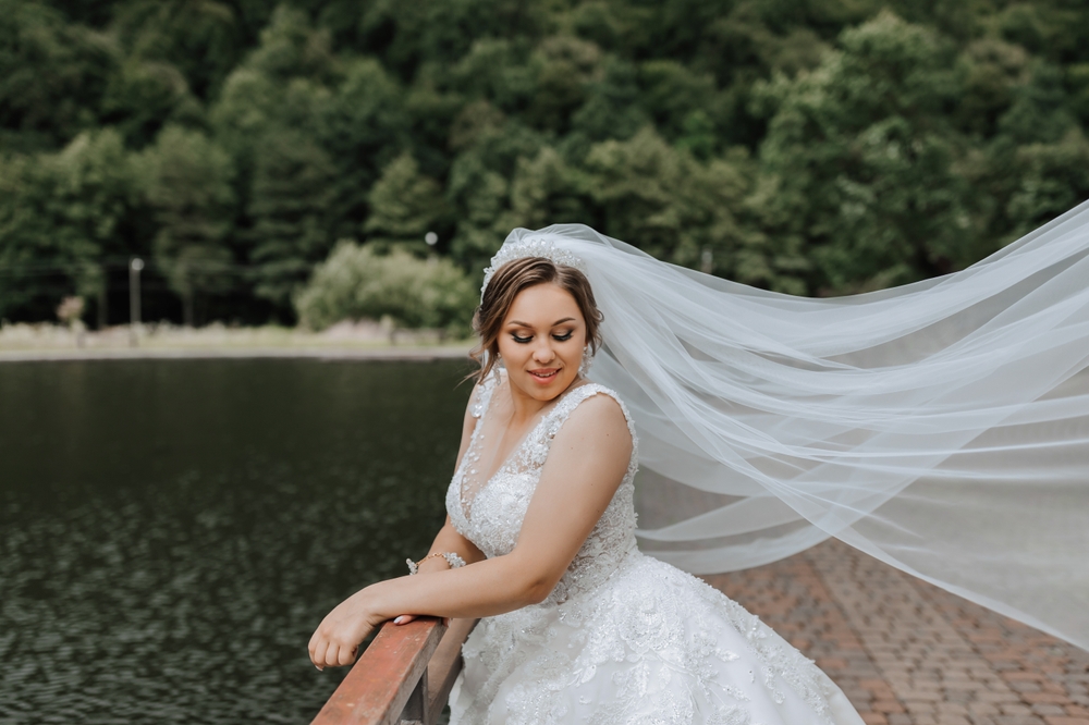 Curvy bride with long, white, tulle veil, flowing in teh wind.