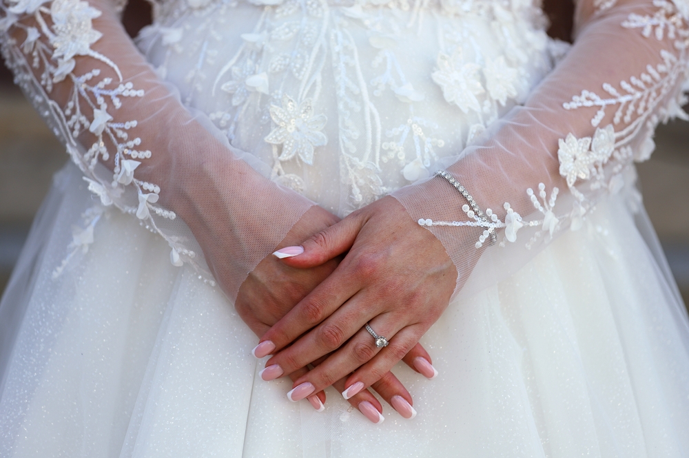 Bride with lace sleeves clasping hands