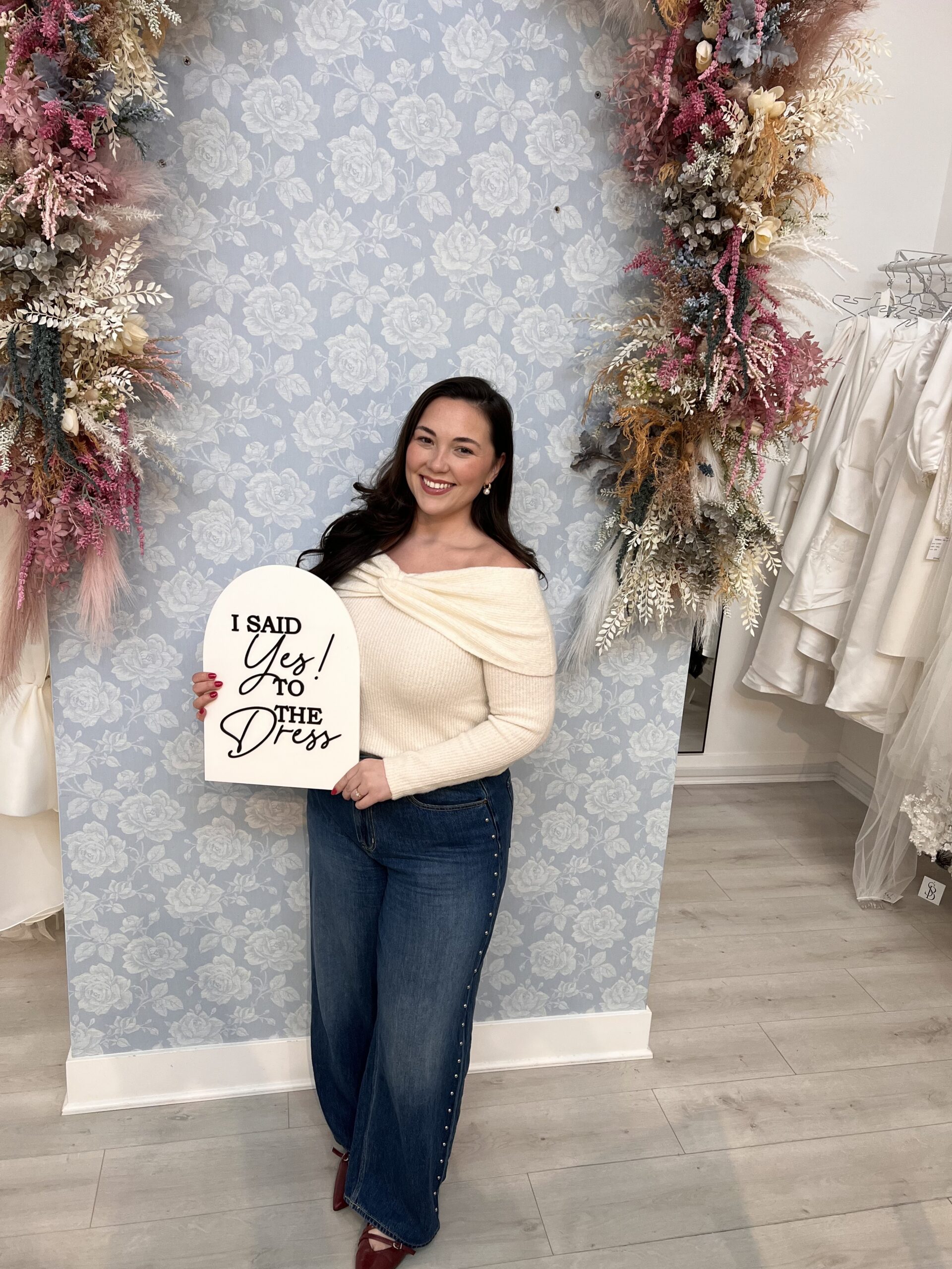 Josie with a happy smile holder a signage of saying yes to the dress at savvy bridal.