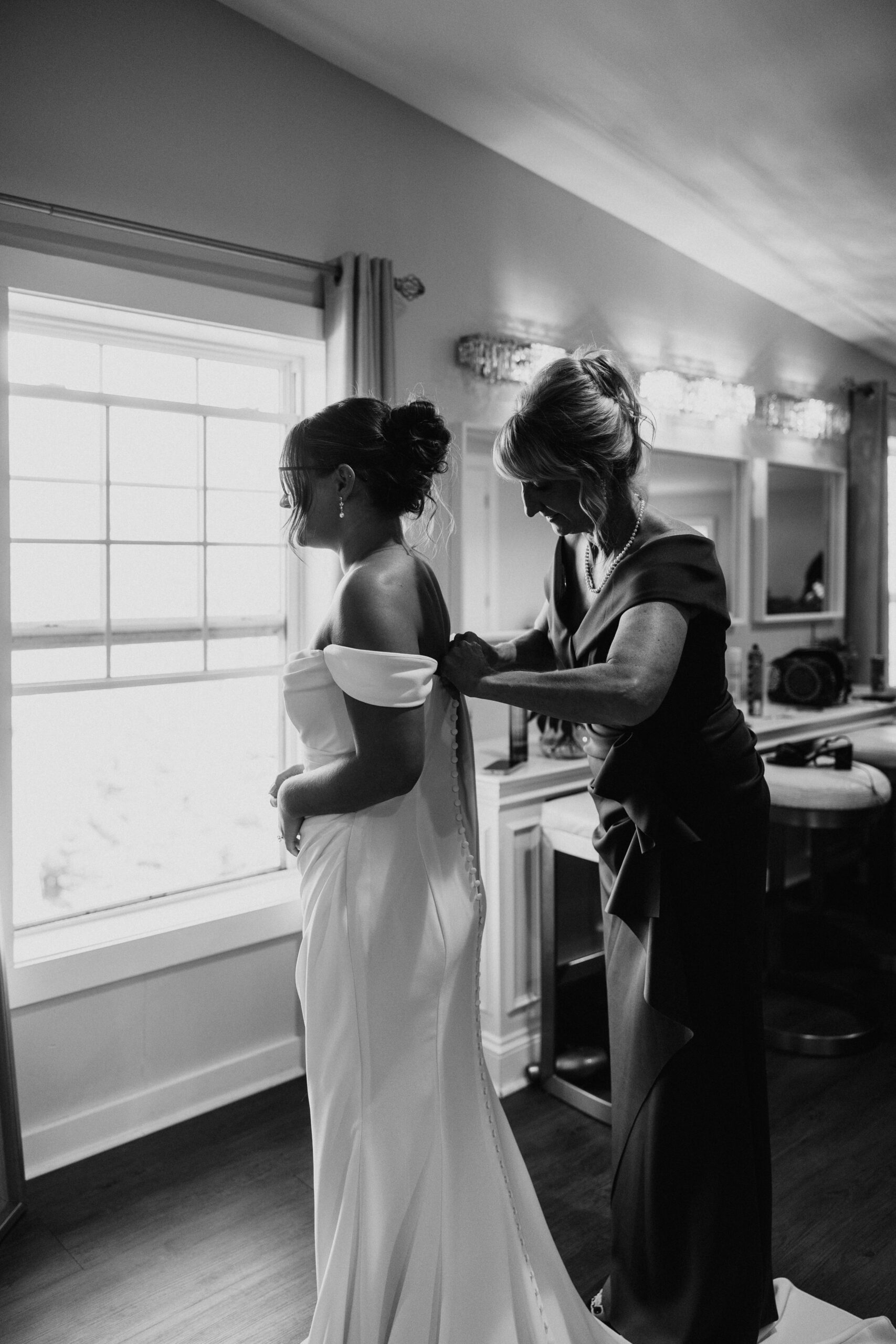 mother assisting her daughter to put on the bridal gown