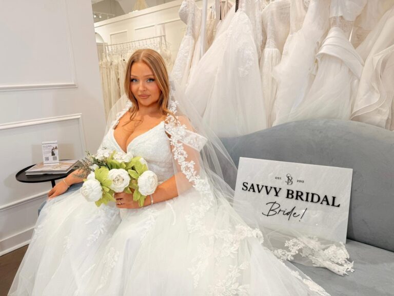 Bride wearing a lace ball gown wedding dress with a cathedral lace veil while celebrating after saying yes to the dress at Savvy Bridal boutique.