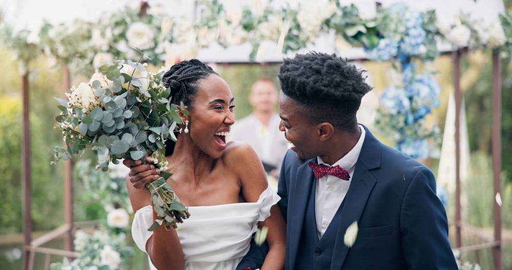 Bride in an off-shoulder wedding dress smiles at the groom