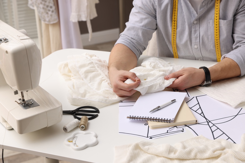 Closeup of tailor's hands as they make alterations to a white wedding dress