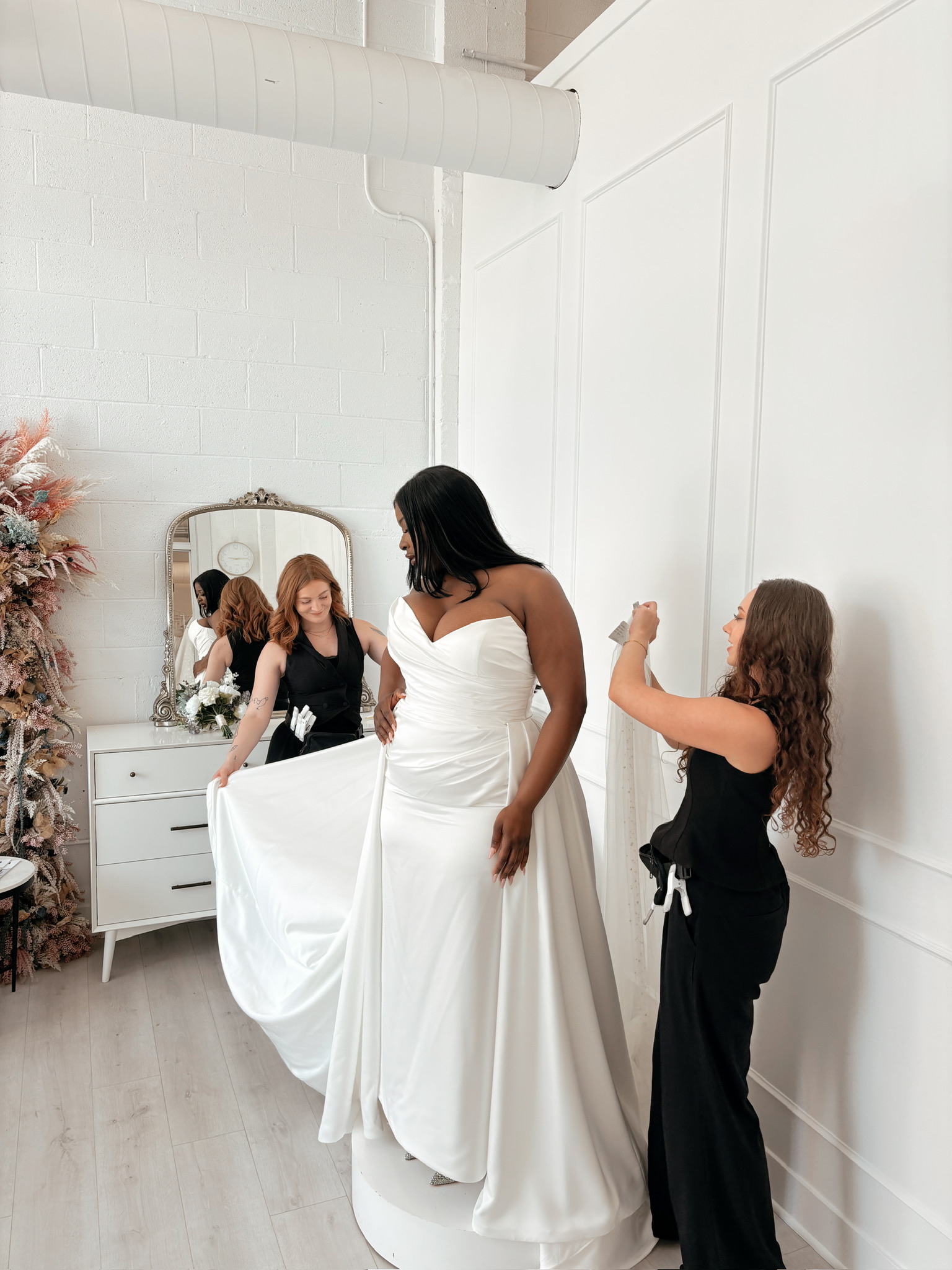 Bride trying on wedding dresses, looking at reflection