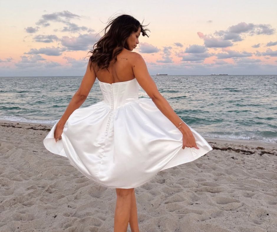 Bride wearing a strapless satin tea-length wedding dress on Fort Lauderdale Beach at sunset.