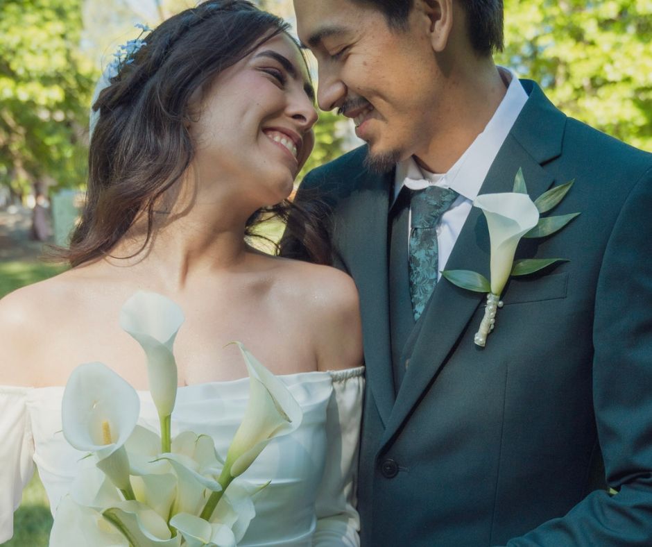 Close-up smiling portrait of couple while bride holding with calla lilies