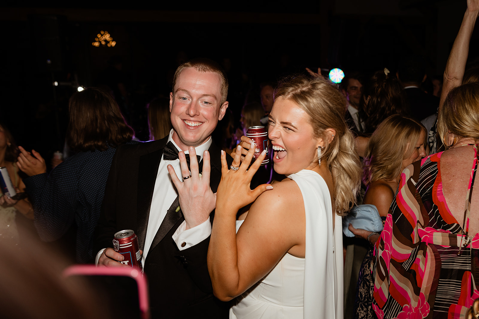 Sydney laughing while showing off her wedding ring, while another catches the couple surrounded by friends on the dance floor.