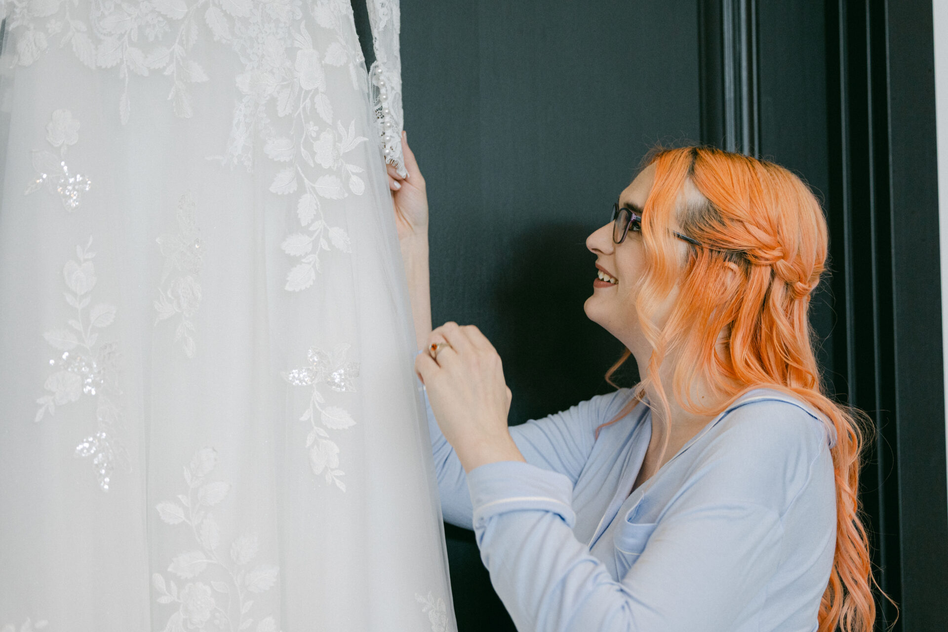 Caitlyn admiring the floral lace details of her wedding dress while getting ready for her wedding to Anna.