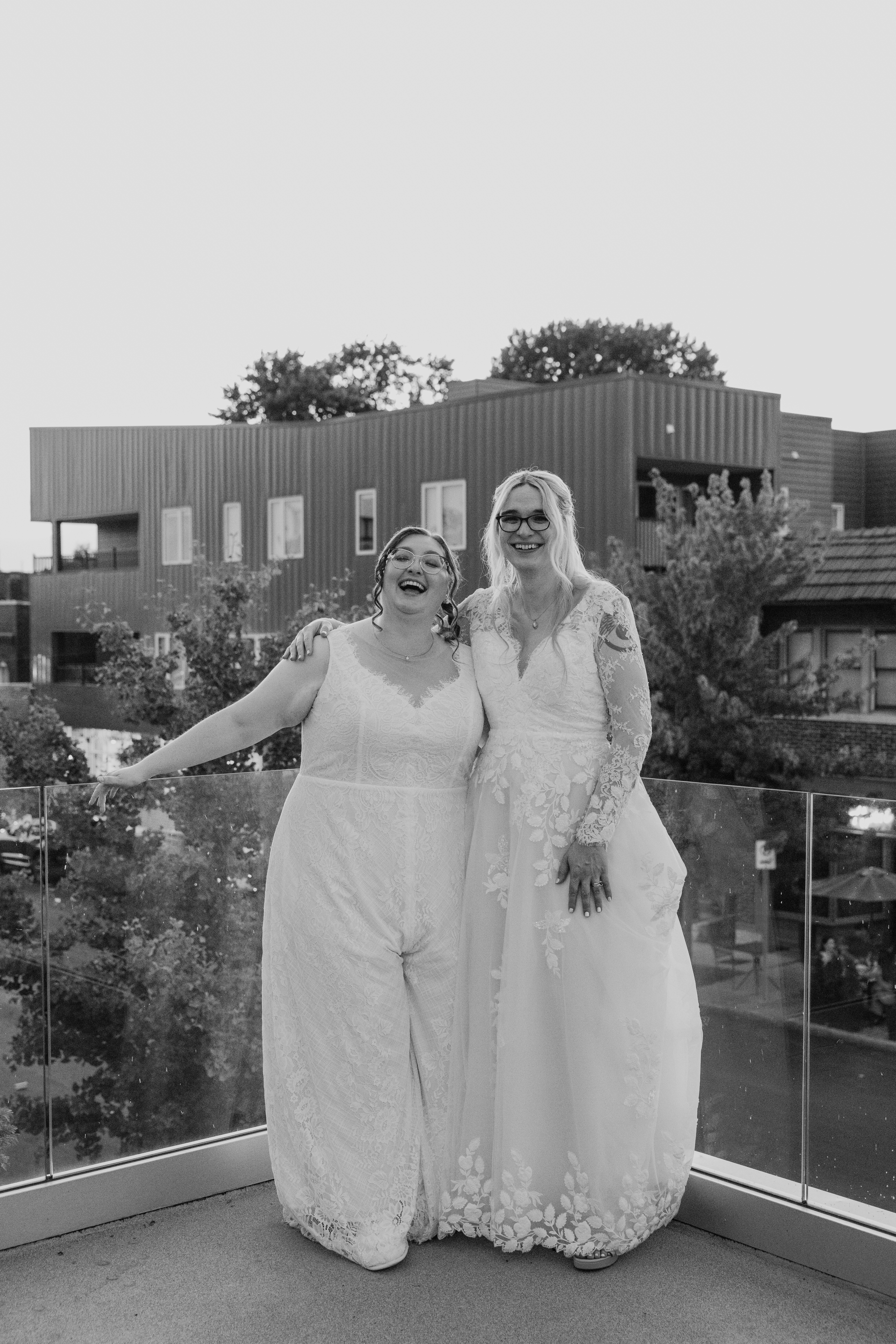 Black-and-white photo of Caitlyn and Anna laughing together outdoors on their wedding day.