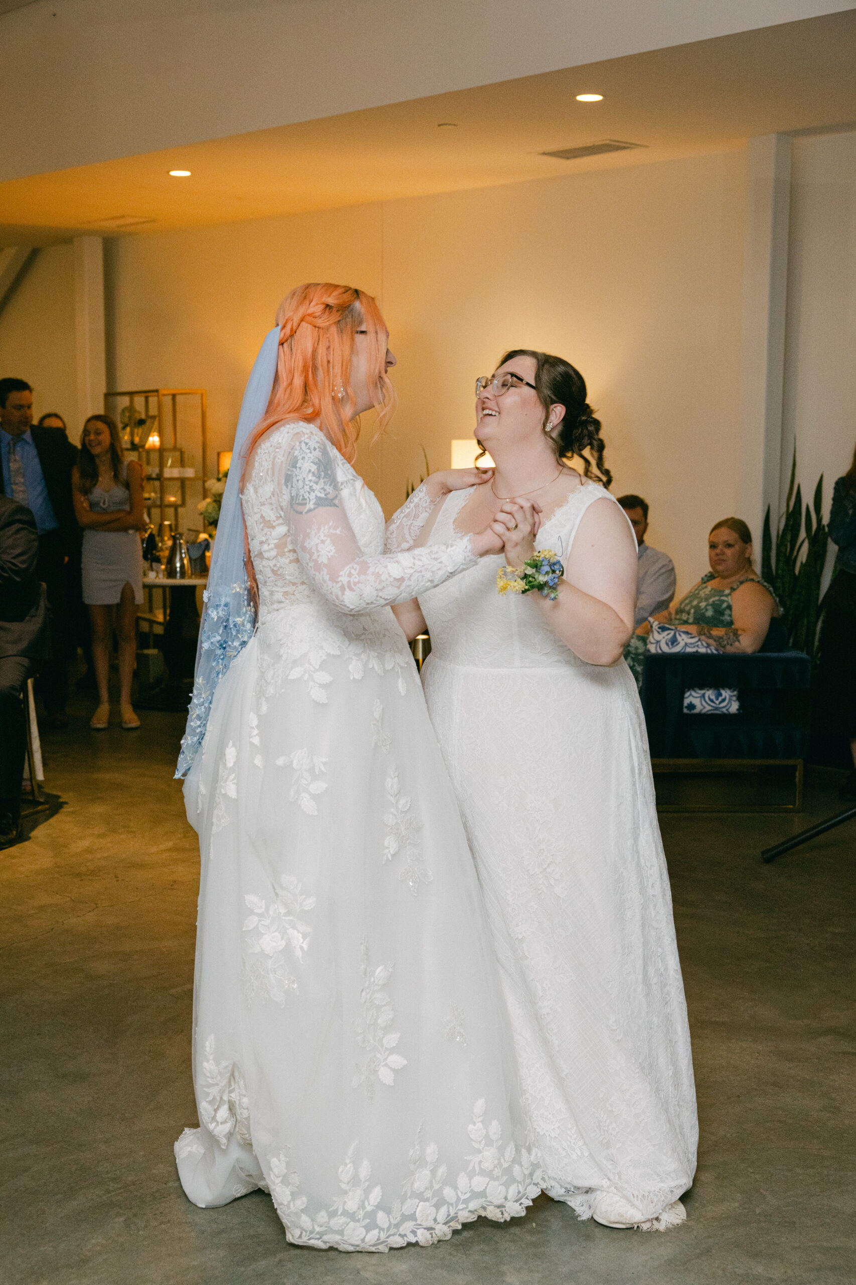 Newlyweds Caitlyn and Anna smiling and dancing together at their wedding reception.