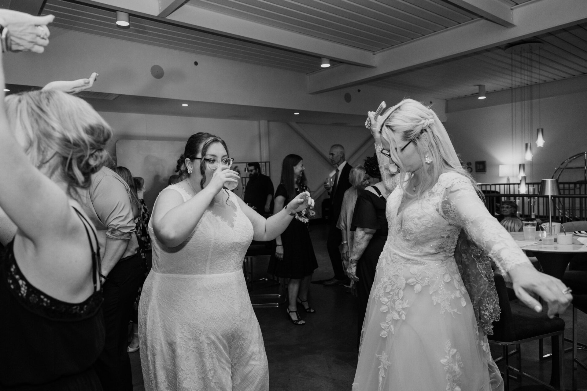 Caitlyn and Anna dancing together in their wedding dresses during their joyful wedding reception surrounded by family and friends.
