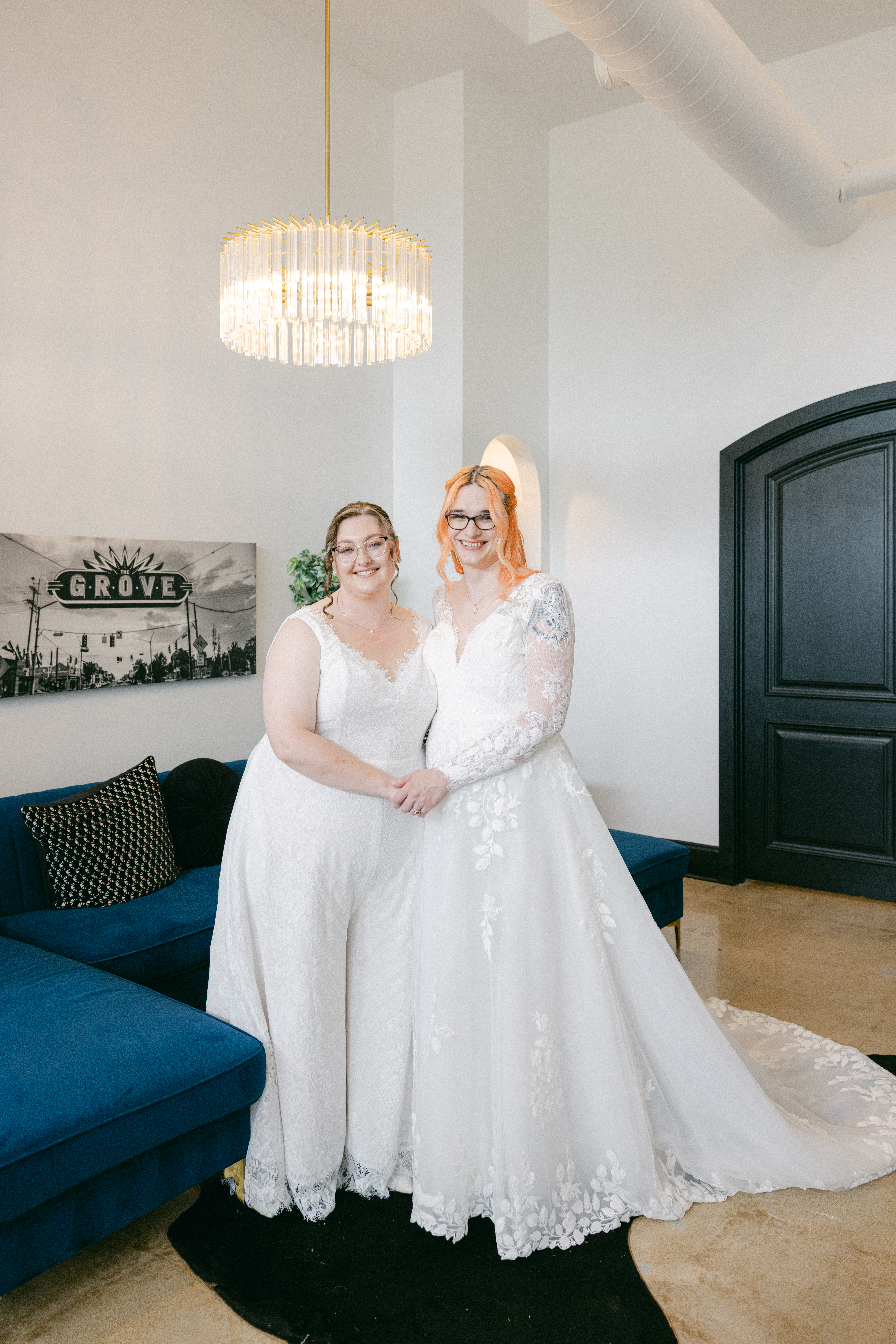 Caitlyn and Anna posing together in their wedding dresses inside their modern wedding venue.