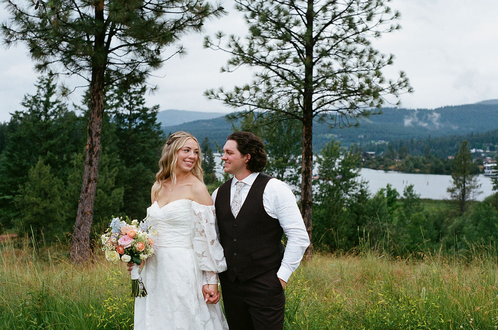 Savvy Bride Katrina and Ryon posing outdoors with a lake and mountain landscape behind them.