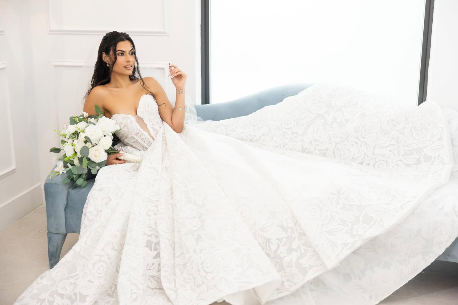 Bride wearing a strapless lace ball gown with a floral bouquet.