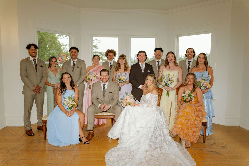 Katrina and Ryon posing with their wedding party in colorful bridesmaid dresses and neutral suits.