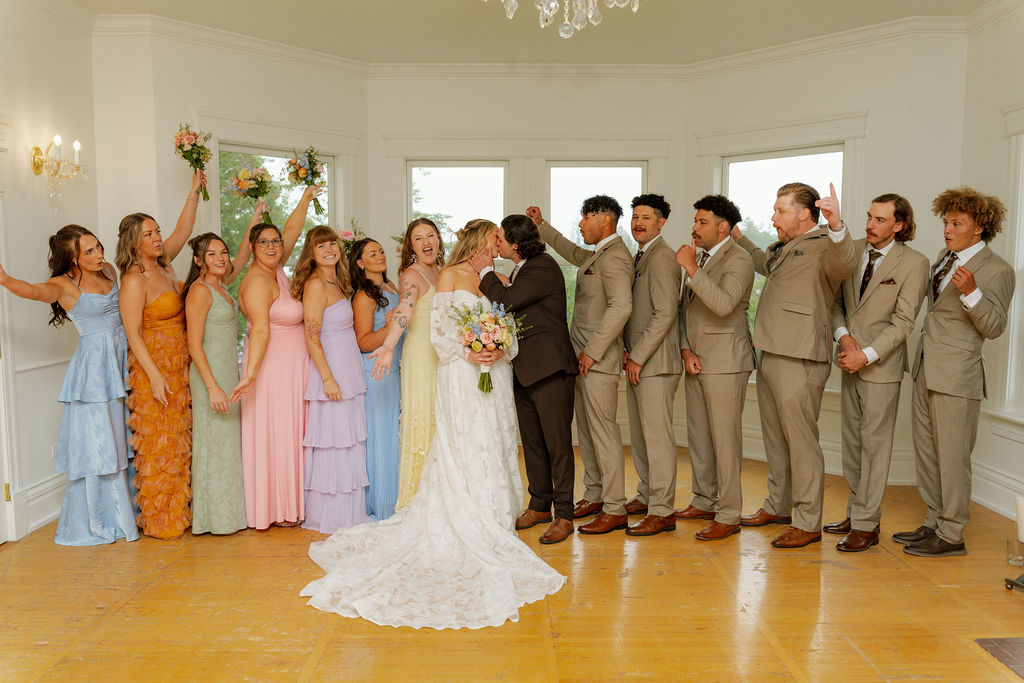 Savvy Bride Katrina and Ryon kissing as their wedding party celebrates around them.