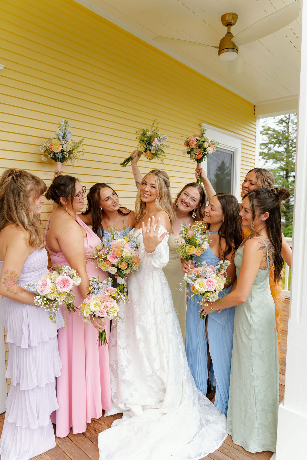 Bride celebrating with bridesmaids in colorful dresses and floral bouquets.