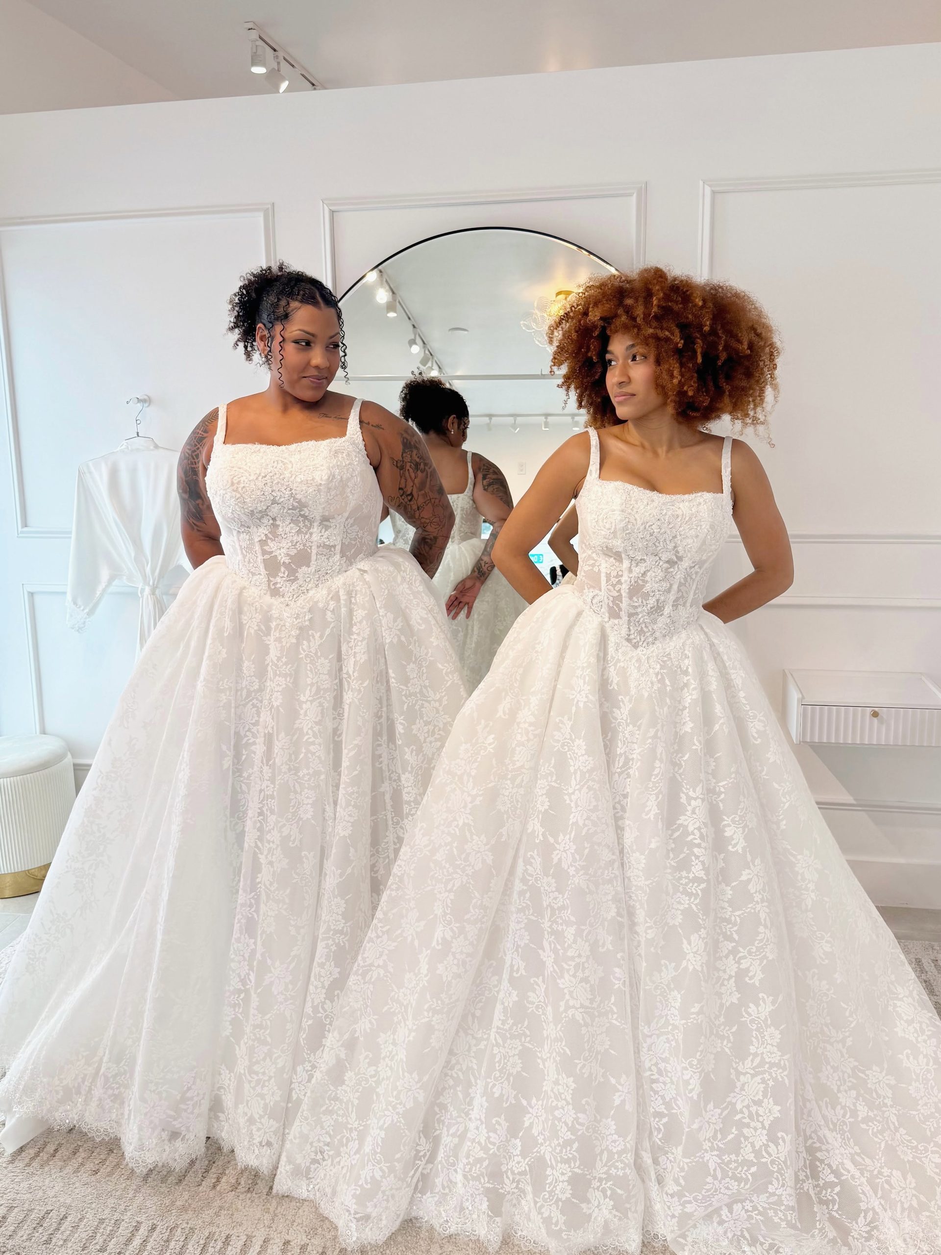 Two brides modeling romantic lace ball gown wedding dresses with full skirts at Savvy Bridal.