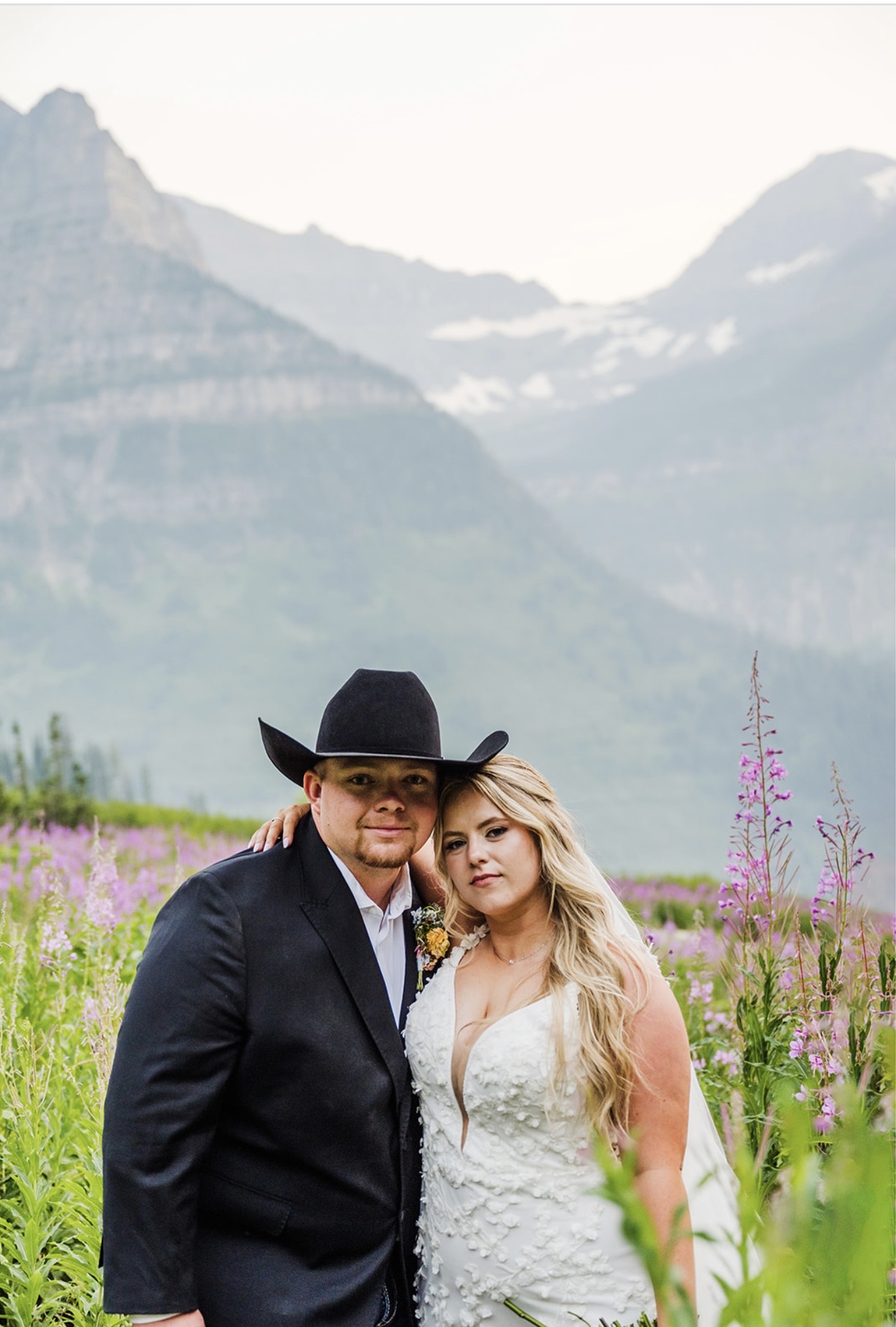Savvy Bride Annabelle and Zack posing in their wedding attire overlooking the mountains and lake at Glacier National Park.