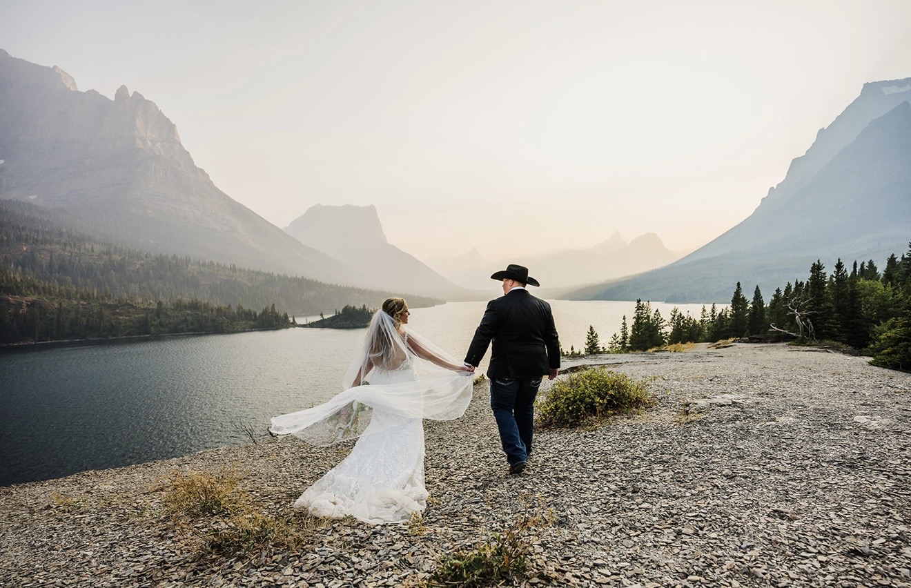 Annabelle and Zack sharing a romantic kiss beneath a towering waterfall during their Glacier National Park wedding.