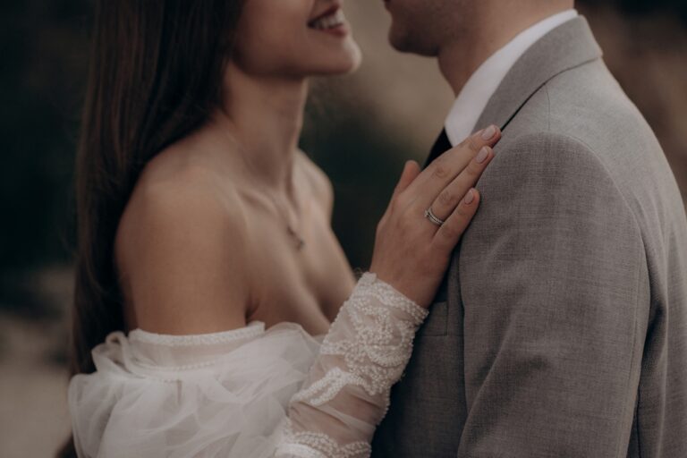 Closeup of happy couple having photoshoot outdoors, kissing. Young groom and bride getting married, smiling, enjoying, having photoshoot. Concept of happiness and family relations.